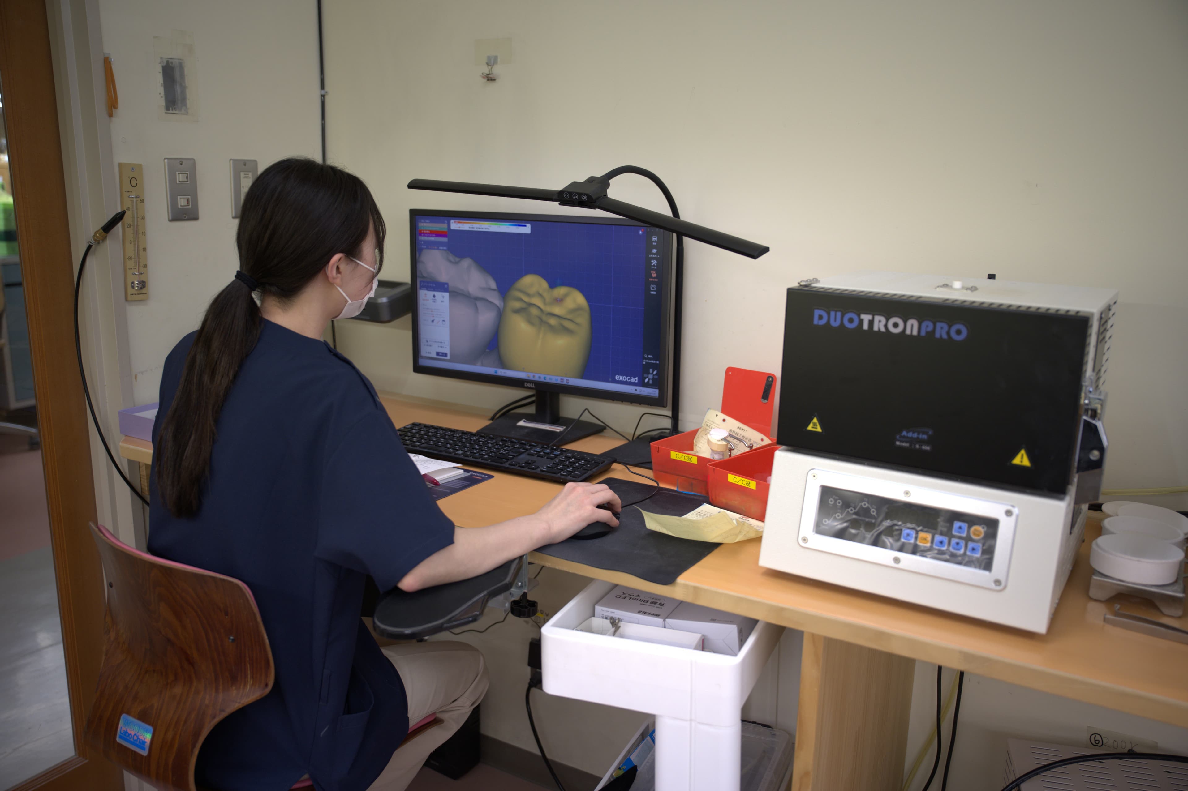 exocadのCAD画面を前にデジタル設計を行う技工士