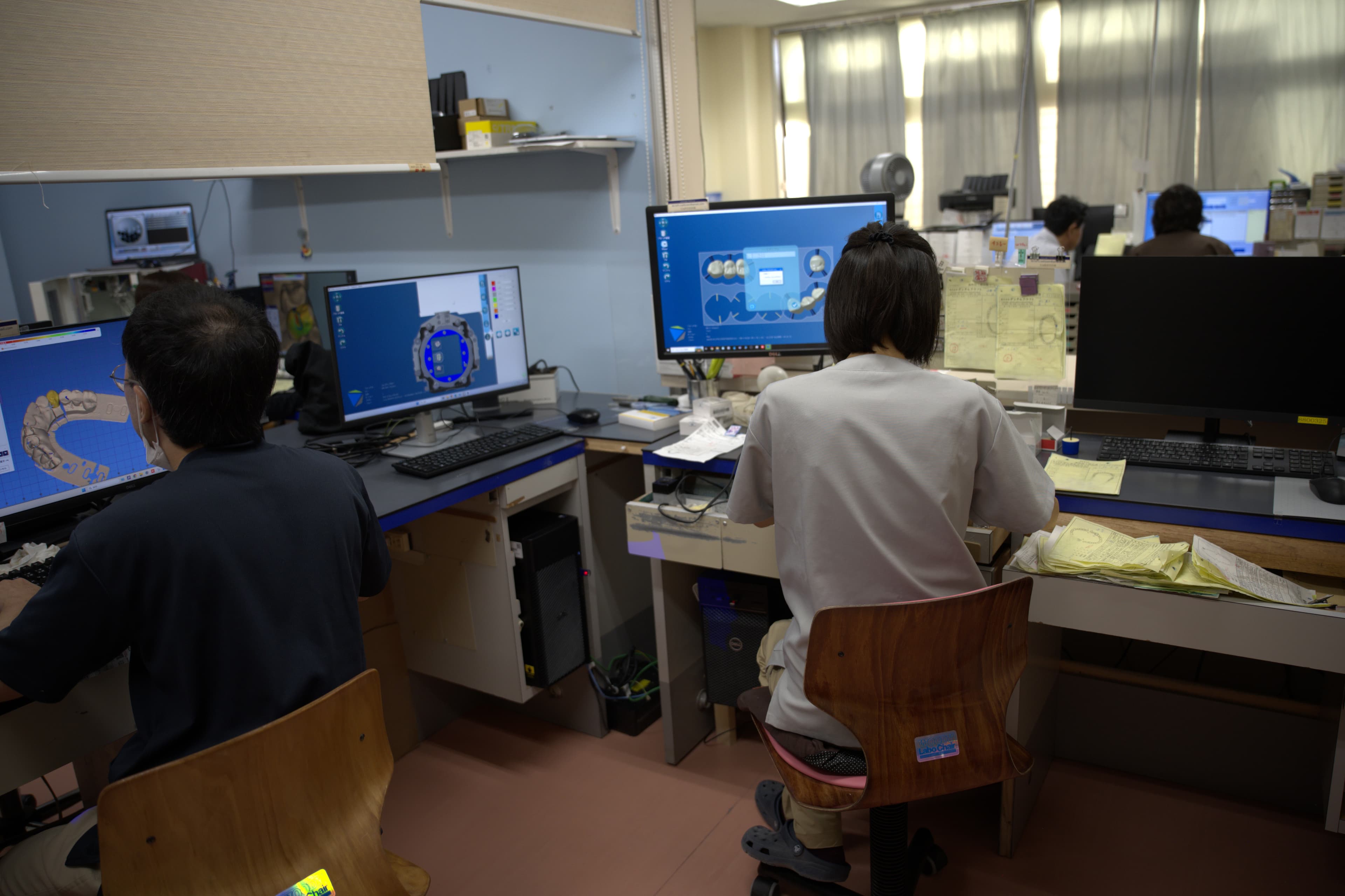 複数のスタッフが作業台に向かう技工室の様子